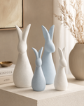 Set of four ceramic bunny sculptures in white and powder blue on a white table