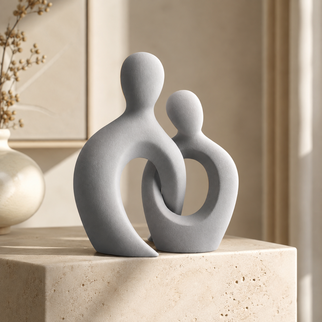 Abstract couple ceramic sculpture in matte grey on a travertine surface