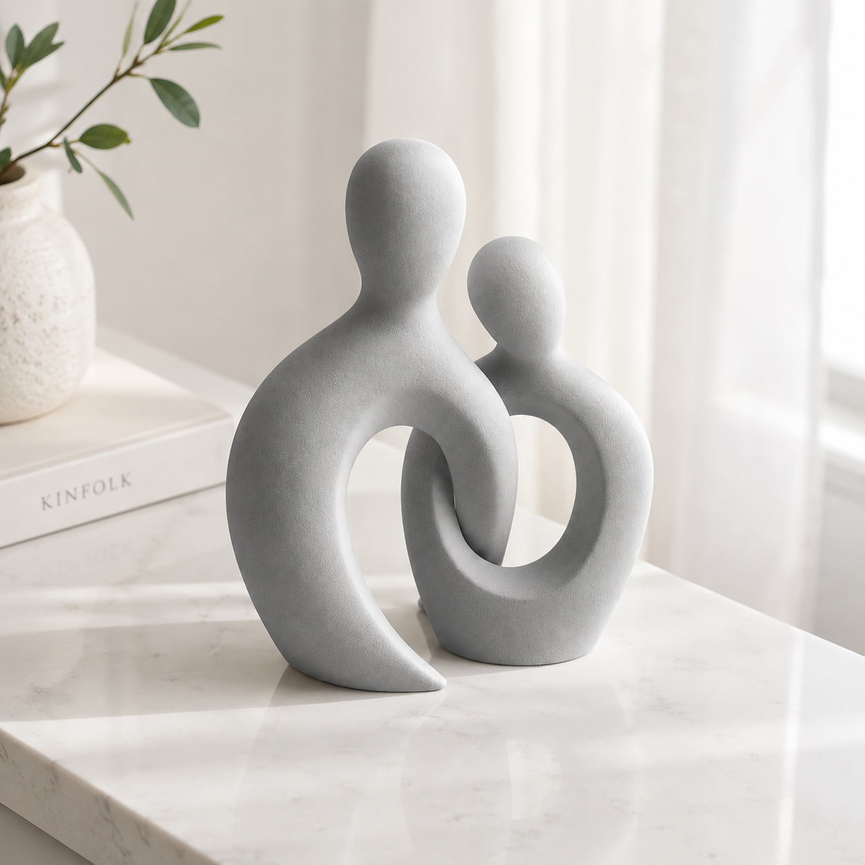 Abstract couple sculpture on a white marble surface with soft natural light