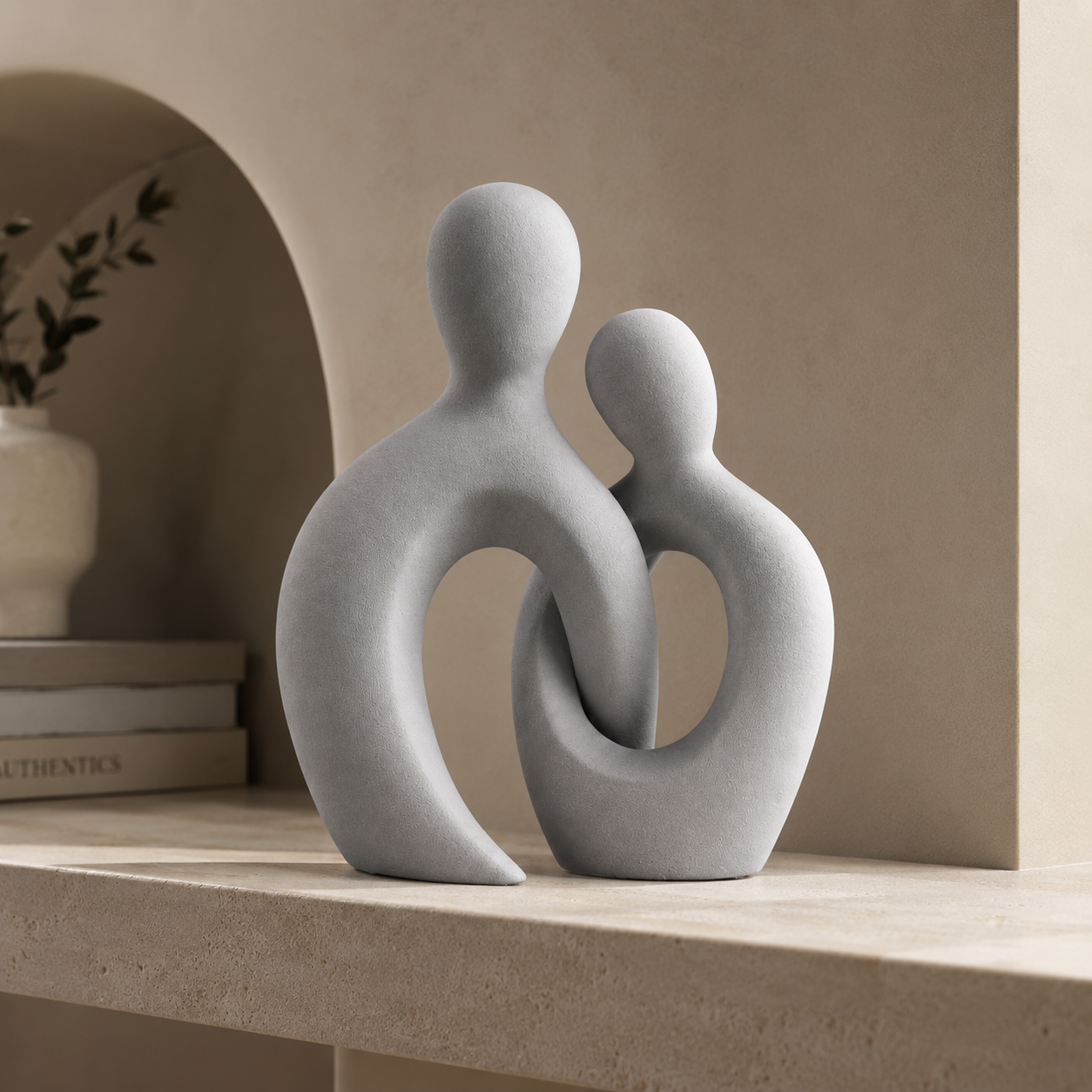 Abstract couple sculpture displayed on a shelf in a neutral arched alcove