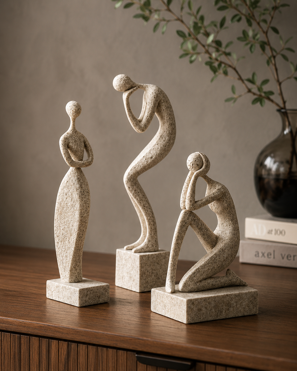 Abstract figure sculpture set displayed on a dark wood sideboard with books