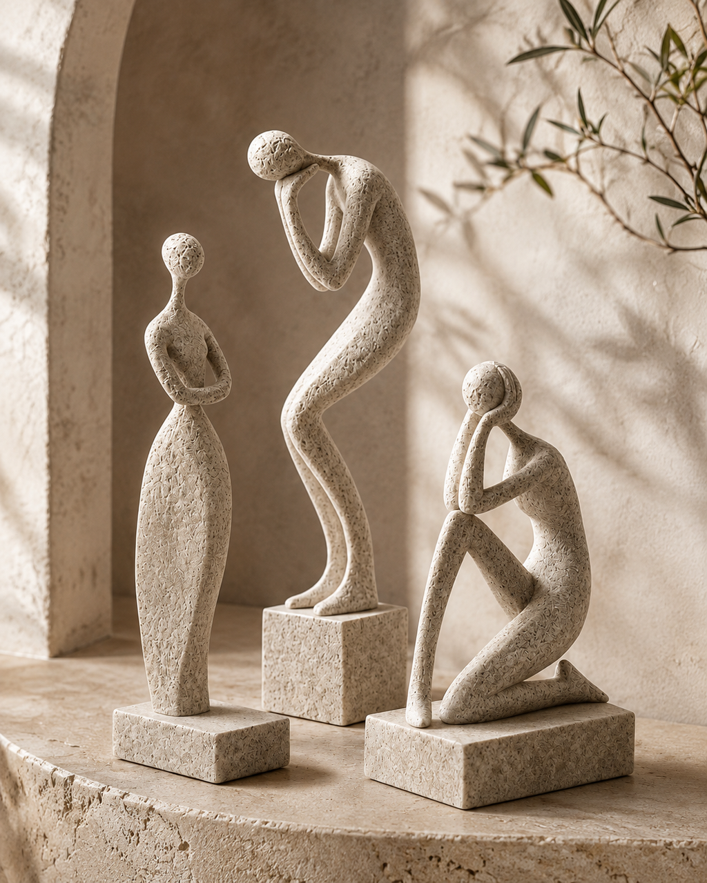 Three abstract ceramic figure sculptures in a Mediterranean arched alcove with olive branch