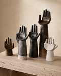 Raised hand ceramic sculptures displayed on a marble surface