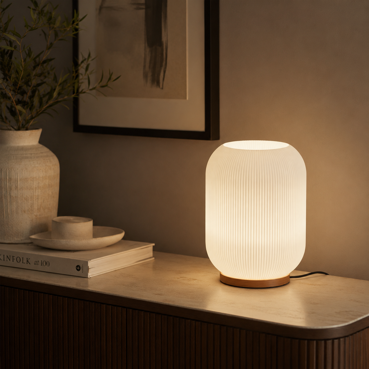 Ribbed glass table lamp on a sideboard with ceramic vase and books in a warm living room