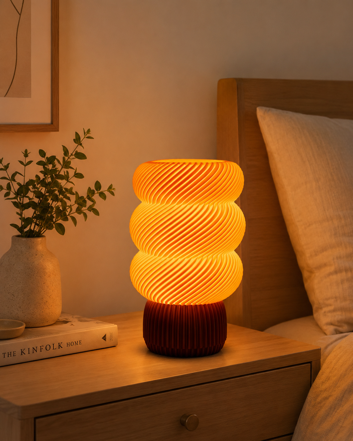 Spiral wave table lamp glowing warm amber on a bedside table with books and a plant