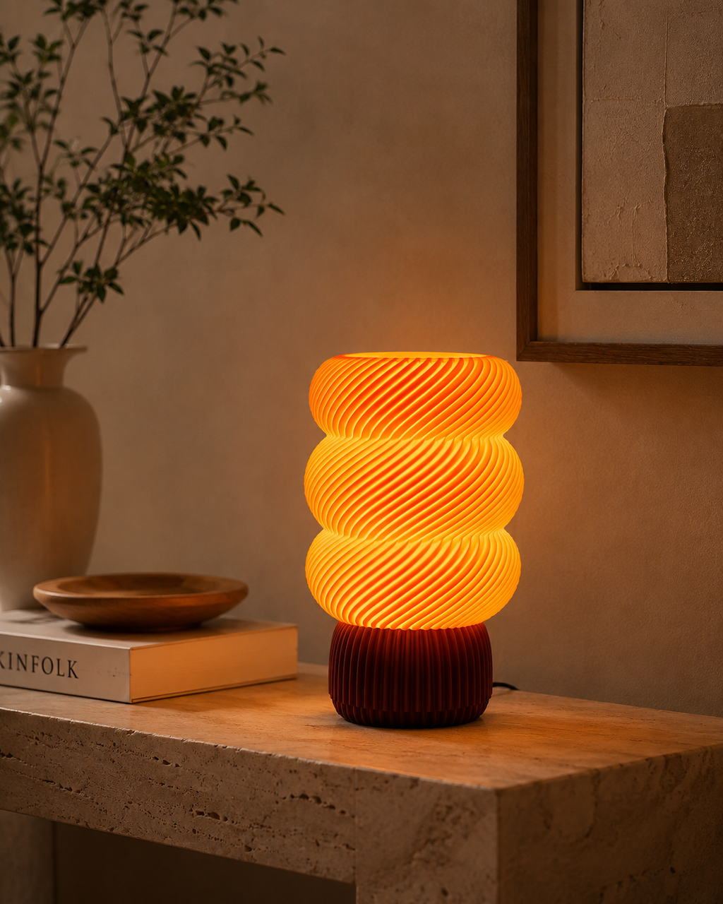 Sculptural spiral wave lamp on a travertine console with ceramic vase and books in a warm living room