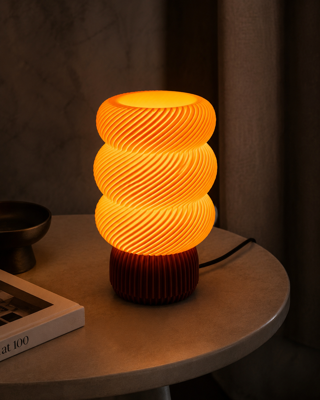 Amber glowing spiral wave lamp on a round side table with dark curtains in the background