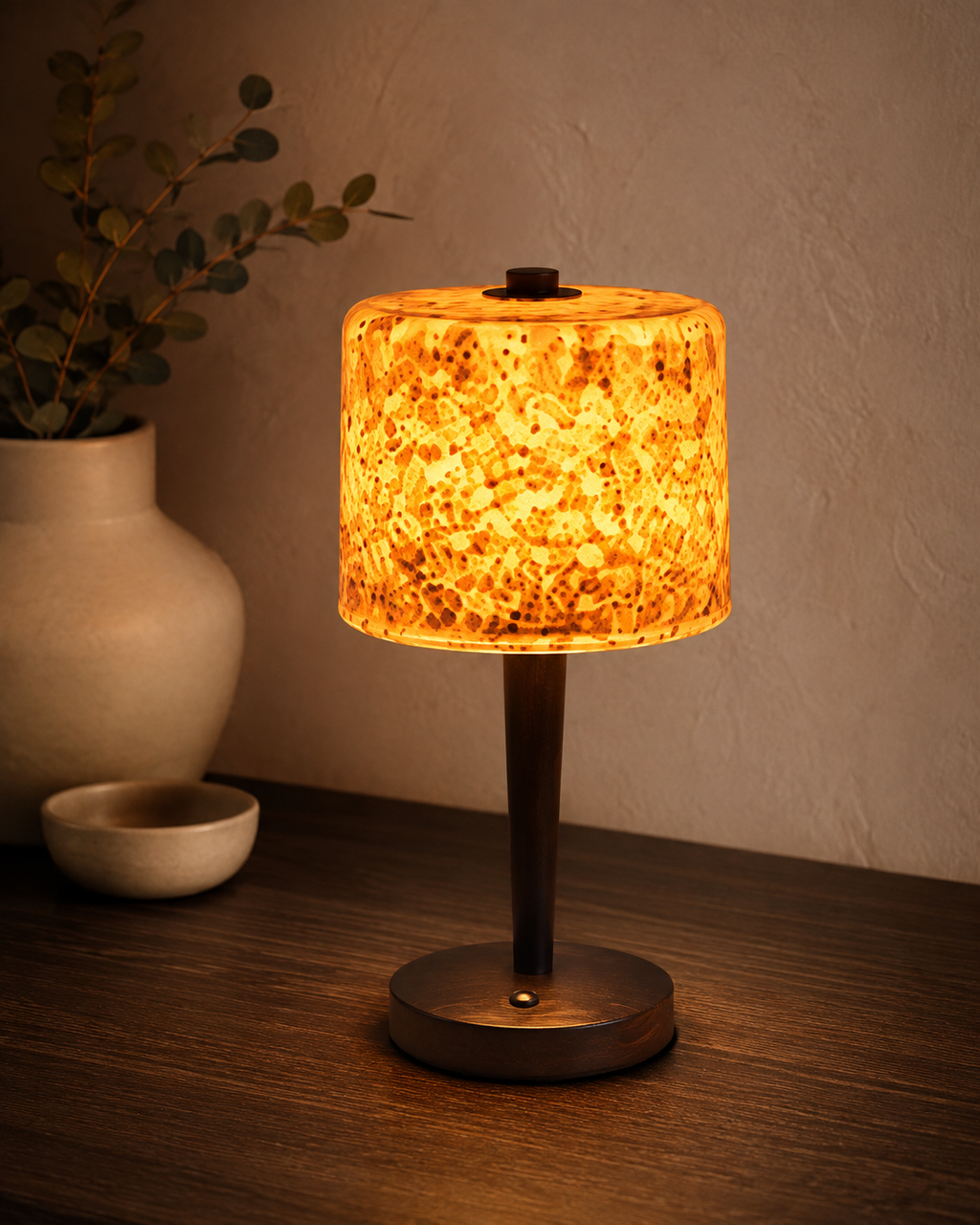Amber speckled glass table lamp on a dark wood console with white ceramic vase and small dish
