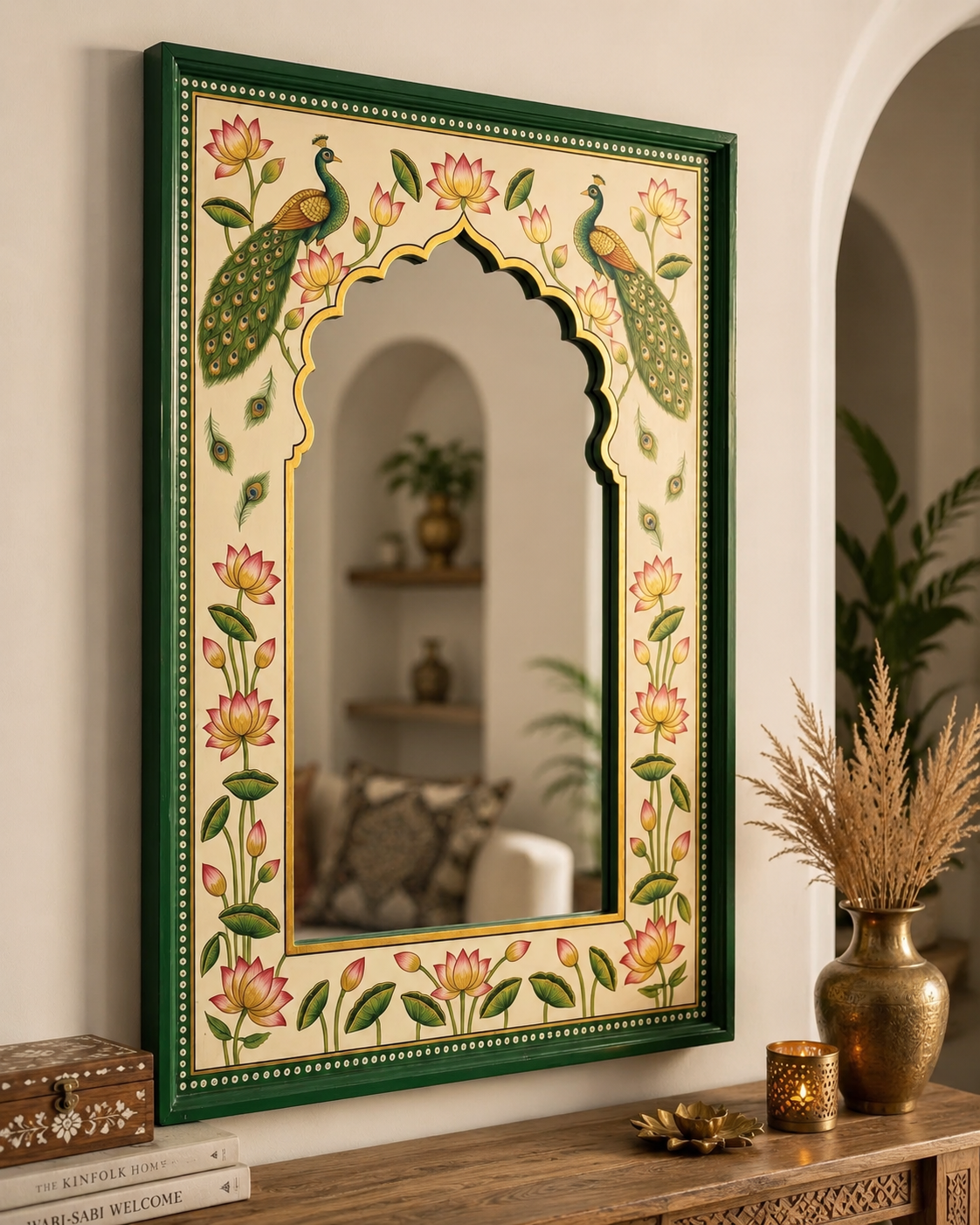 Rajasthani peacock and lotus mirror on a white wall styled with brass vase and pampas grass