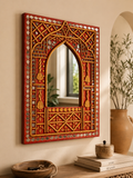 Rajasthani hand-carved mirror work wall mirror with Mughal arch above a wooden console with ceramic bowl and books